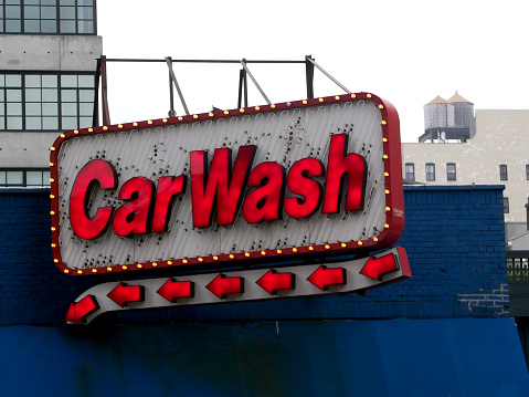 A red and white neon car wash sign hangs on a blue rooftop.