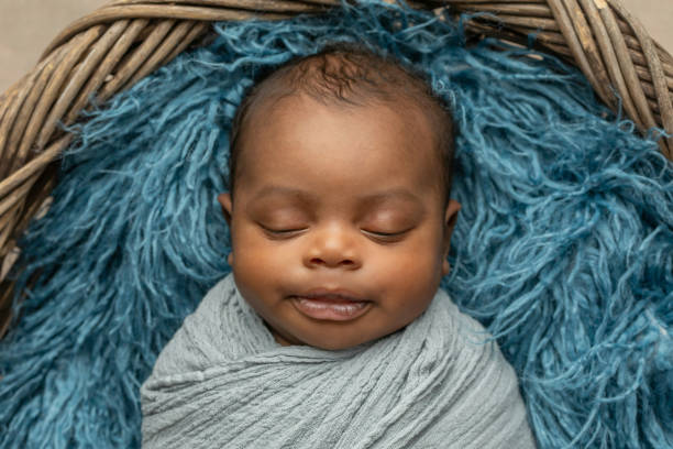 süß schlafende afroamerikanische neugeborene junge in einer decke gewickelt und in einem korb liegend - baby blanket fotos stock-fotos und bilder