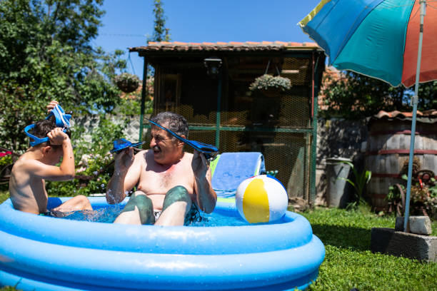 istock Grandfather and grandson playing in an inflatable pool 1264165819