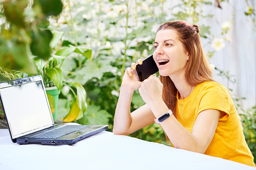 young caucasian woman using smartphone outdoors over green environment background. smiling girl resting outdoors. freelance and e-learning lifestyles conceptual.