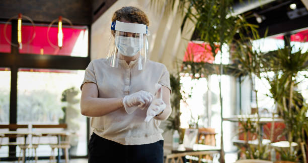istock Waitress Wearing PPE Putting on Gloves 1264166860