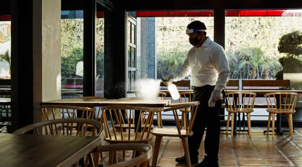 istock Waiter Wearing PPE During Covid-19 Pandemic Spraying Tables 1264166862