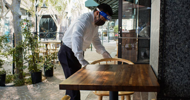 Waiter Sanitizing Chairs During Covid-19 Pandemic