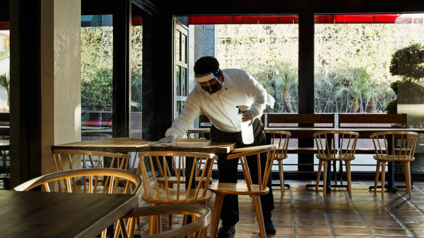 istock Waiter Wearing PPE During Covid-19 Pandemic Sanitizing Tables 1264167831