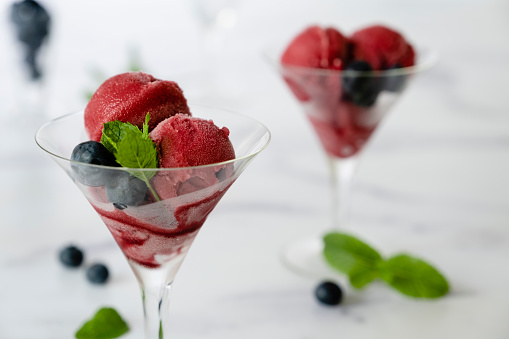 Raspberry sorbet served in martini glasses with blueberries and mint.