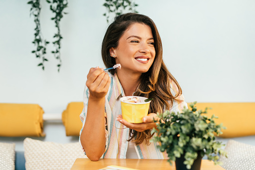 Beautiful and happy brown hair woman enjoying in eating delicious handmade rolled ice cream.