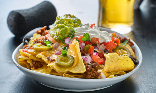 plate of loaded nachos with queso cheese plate of loaded nachos with queso cheese close up nachos stock pictures, royalty-free photos & images