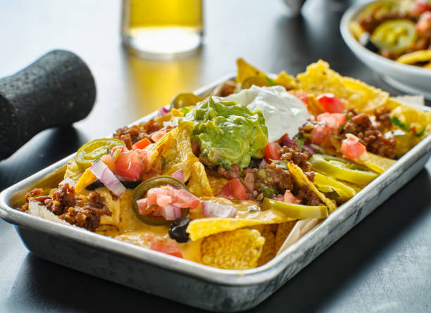tray of loaded mexican nachos with beef and queso cheese tray of loaded mexican nachos with beef and queso cheese close up nacho chip stock pictures, royalty-free photos & images