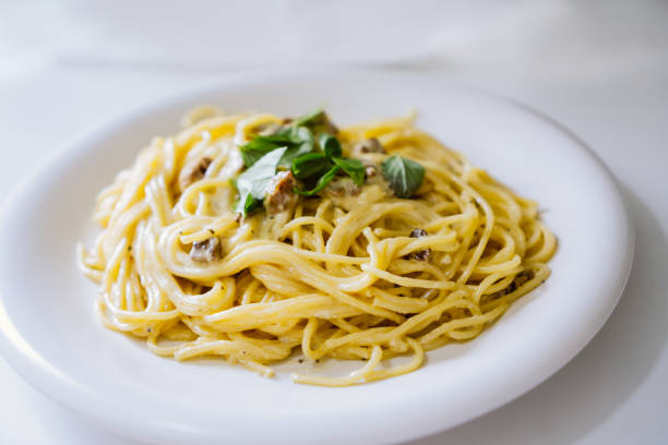 istock Homemade spaghetti Carbonara with pieces of bacon and basil. Fork on the side 1264185751