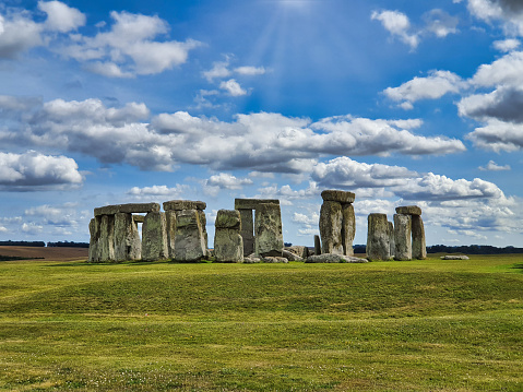 Close-up view of ancient stones during sunset at UNESCO World Heritage Site at Stonehenge, Wiltshire, UK. Sun shines through the stones. Major tourist destination, archeological and pilgrimage site during Summer Solstice and Winter Solstice. Visible grain, softer focus.