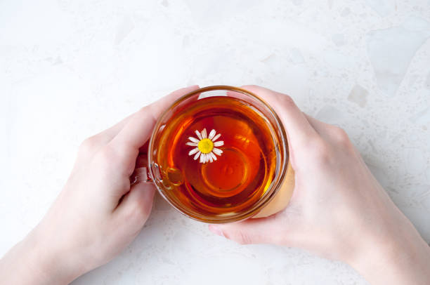 istock Hands holding a Cup of chamomile tea on the table, top view 1264194358
