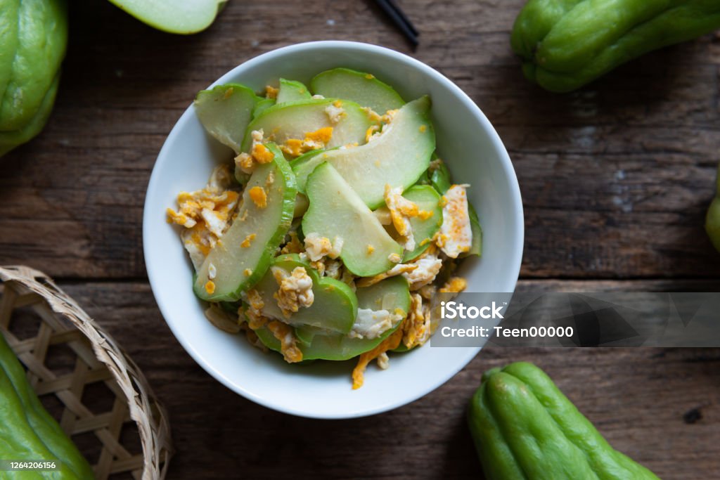 Fresh chayote fruits (Sechium edulis) stir fried with egg and garlic in bowl on wood background Fresh chayote fruits (Sechium edulis) stir fried with egg and garlic in bowl on wooden background Alligator Stock Photo