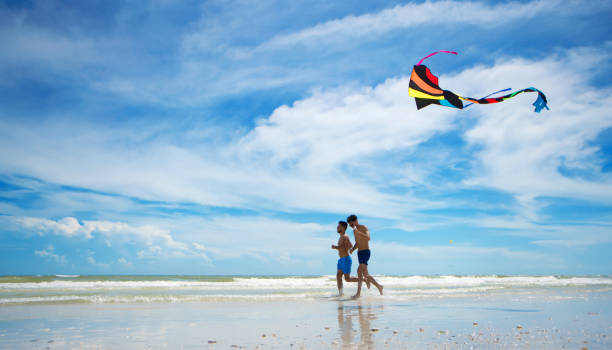 pareja lgtb hispana volando una cometa en una playa vacía florida - florida mid air miami florida people fotografías e imágenes de stock