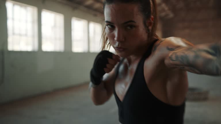 Female athlete training boxing moves in empty factory