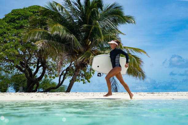 Female bodysurfer in the tropics Sporty bodyboarder runs across a tropical beach 8564 stock pictures, royalty-free photos & images