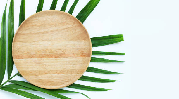 istock Empty white wooden plate on tropical palm leaves on white background. 1264211290