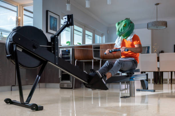 Young man wearing a liza mask during a rowing machine session