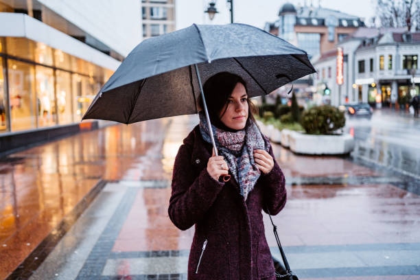 istock Woman walking downtown in rain 1264218994