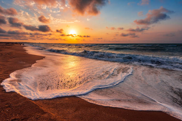 farbenfrohen sonnenuntergang am strand - romantic sky stock-fotos und bilder