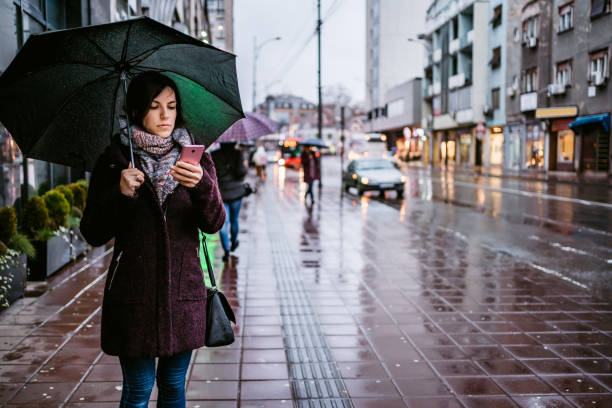 istock Woman checking messages on phone in rain 1264219089
