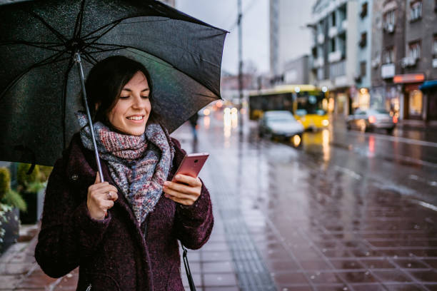 istock Woman checking messages on phone in rain 1264219103
