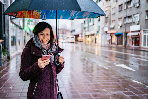 istock Woman checking messages on phone in rain 1264219112