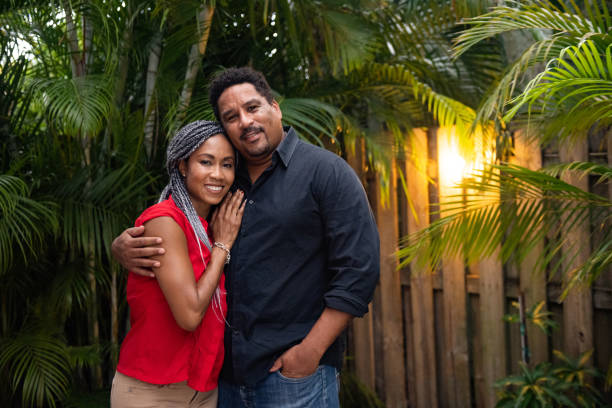 Beautiful Married African American Couple Standing Together in Their Backyard in Miami Florida This is a photograph of a loving African American couple in their 40s standing close together in their lush backyard in Miami, Florida at dusk in summer. weaving photos stock pictures, royalty-free photos & images