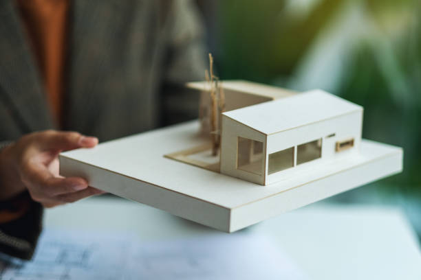 istock An architect holding and working on an architecture house model with shop drawing paper 1264223395