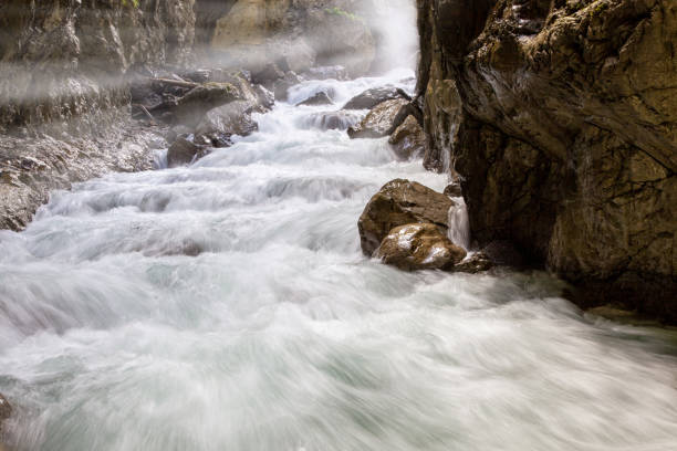 water flowing over rocks with sunrays. Scenic view of smooth flowing water in Partnach Gorge in Partnachklamm, Garmisch Partenkirchen, Bavaria, Germany partnach gorge stock pictures, royalty-free photos & images
