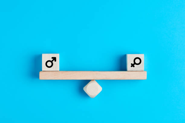 Concept of gender equality. Wooden blocks with male and female symbols on a balanced seesaw Concept of gender equality. Wooden blocks with male and female symbols on a balanced seesaw on blue background. gender stereotypes stock pictures, royalty-free photos & images