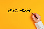 Male hand is writing the concept of growth hacking on yellow background