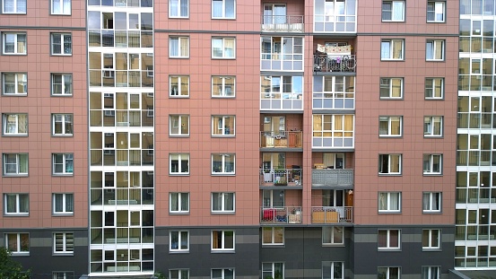 Facade of a new multi-story residential building. Sale and rental of economy class apartments and comfortable housing. Cityscape. Windows and balconies. City living. Real estate. Mortgage concept.