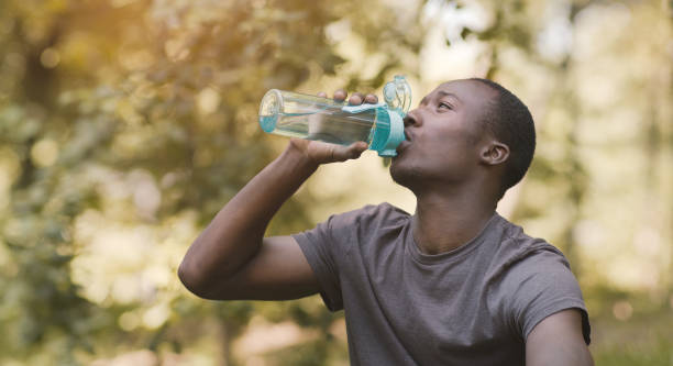 istock Young black man drinking water from sport bottle at park 1264226753