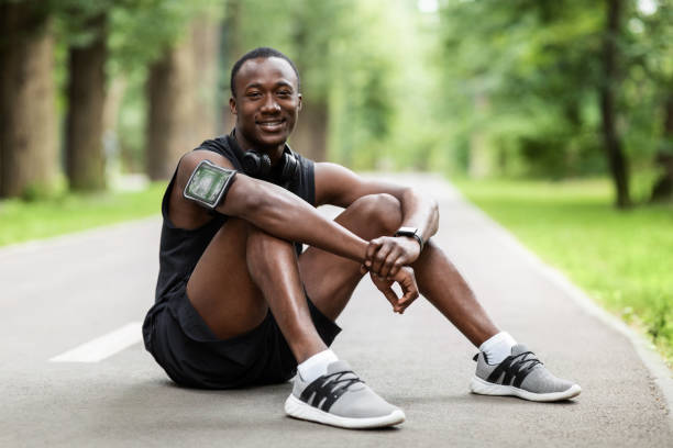 istock Happy sporty guy having rest after jogging, sitting on path 1264226784