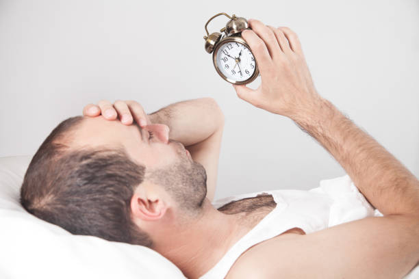 istock Man laying in bed, while looking to alarm clock. 1264226936