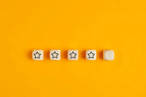 Photo of Wooden cubes with four stars out of five. Concept of service rating and evaluation.