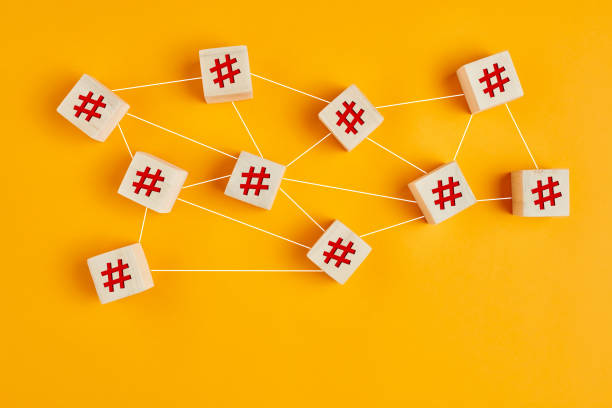 símbolos de hashtag em cubos de madeira conectados uns aos outros com linhas no fundo amarelo. conexão com hashtag, pesquisa ou trending topic no conceito de mídia social. - computer network social issues social networking sharing - fotografias e filmes do acervo