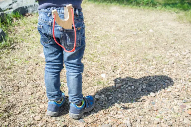 3 years little boy with slingshot in the jeans pocket. Enjoy toy in nature concept