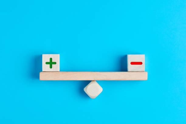 Plus and minus or positive and negative symbols on wooden blocks are in balance on a wooden seesaw Plus and minus or positive and negative symbols on wooden blocks are in balance on a wooden seesaw. Blue background, flat lay view. Pros and cons equilibrium in decision making under uncertainity. stability stock pictures, royalty-free photos & images