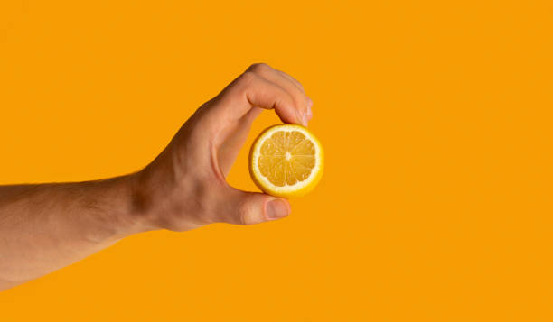 istock Young man showing cut lemon fruit over orange background, closeup with space for text 1264228036