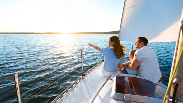 Family Sitting On Yacht Deck Sailing Across The Sea Sea Cruise. Family Sitting On Yacht Deck Sailing Across The Sea On Summer Vacation. Panorama, Copy Space sailing couple stock pictures, royalty-free photos & images