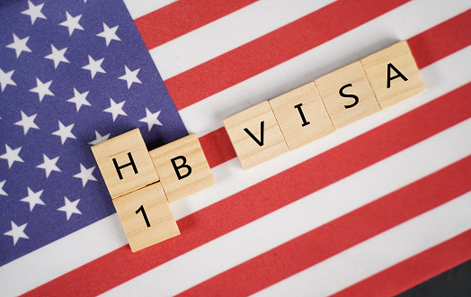 Concepto de Visa H1b para trabajadores extranjeros que muestran letras de madera con la bandera de los Estados Unidos o Estados Unidos como fondo. photo