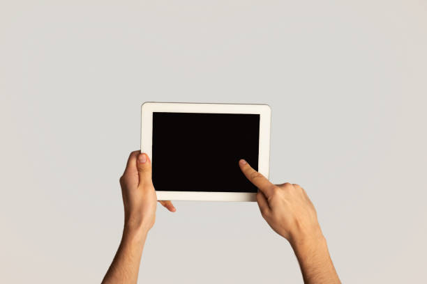 istock Unrecognizable man touching screen of modern tablet computer on light background, mockup for design 1264231924