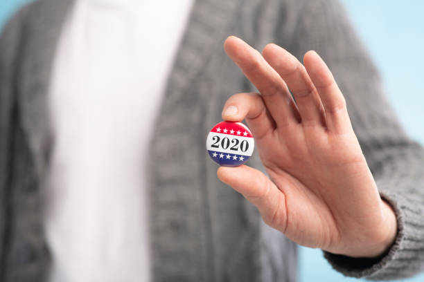 istock Incognito voter holding vote button on blue background 1264232063