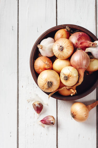 istock Onions and garlic on a white wooden background. 1264232894