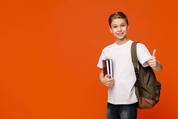 istock Cheerful teen boy with backpack and books gesturing thumb up 1264238267