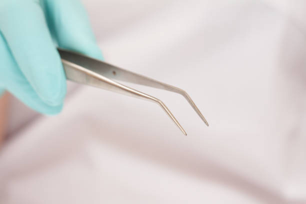 istock Dentist's hand with tweezers on blurred background.. 1264238639