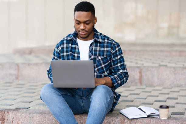 istock Man using laptop, sitting on the steps in city 1264238951