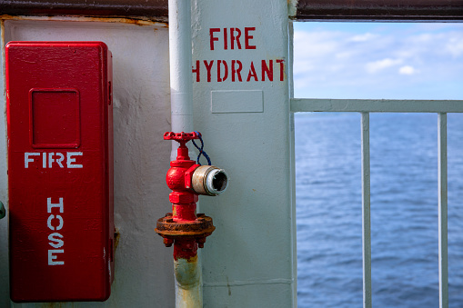 Fire hose and fire hydrant on ferry. Safety first on maritime vessel. Cargo or passenger shipping by sea. Transport vessel safety equipment. Fire on ship protection. Fire prevention concept