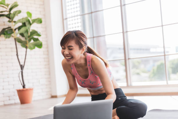 istock Asian female happy laughing learning yoga training from internet, New normal exercise lifestyles 1264242453